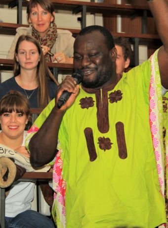 Un étudiant de Sierra Léone souriant tenant un microphone dans un amphithéâtre